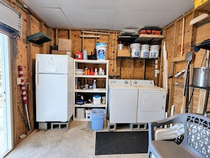 A compact utility room with a refrigerator, stacked bins, and a washing machine.