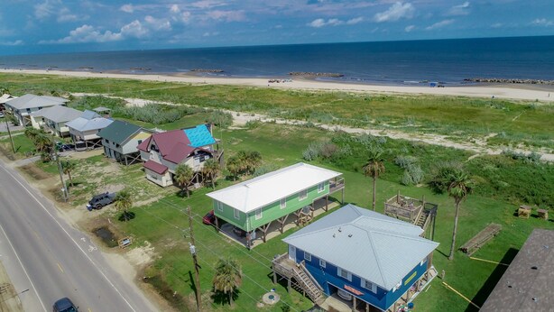 An aerial view of a coastal residential area with houses, a beach, and a road. - Camp PJs - Coastal Realty Group (Grand Isle)