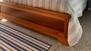 Un dormitorio con cama de madera, ventilador de techo, ventana con persianas y vista al exterior.