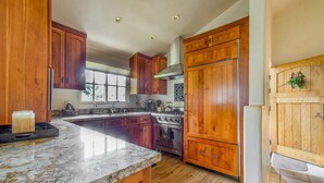 A kitchen with wooden cabinets, a granite countertop, a stainless steel oven, and a refrigerator.