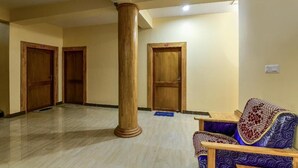 A lobby with wooden doors, a marble floor, and a patterned sofa. - Blue Ocean Resort (Port Blair)