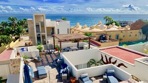 Una terraza en la azotea con mobiliario exterior, piscina y vistas al océano.