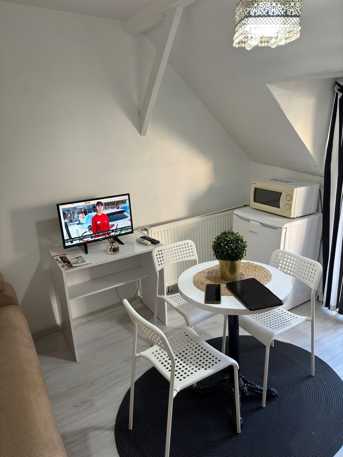 Una habitación moderna y luminosa con comedor, televisión y microondas.