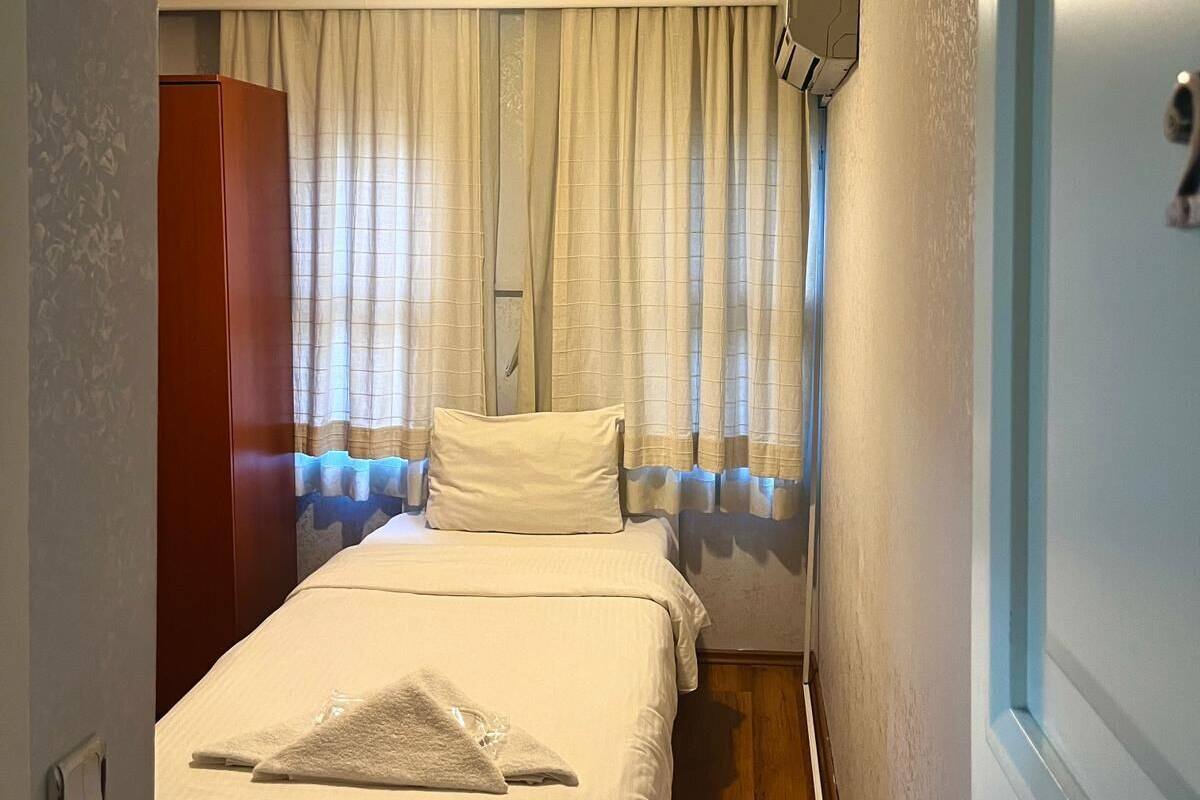 A hotel room with a bed, a wardrobe, a television, and a window with curtains.