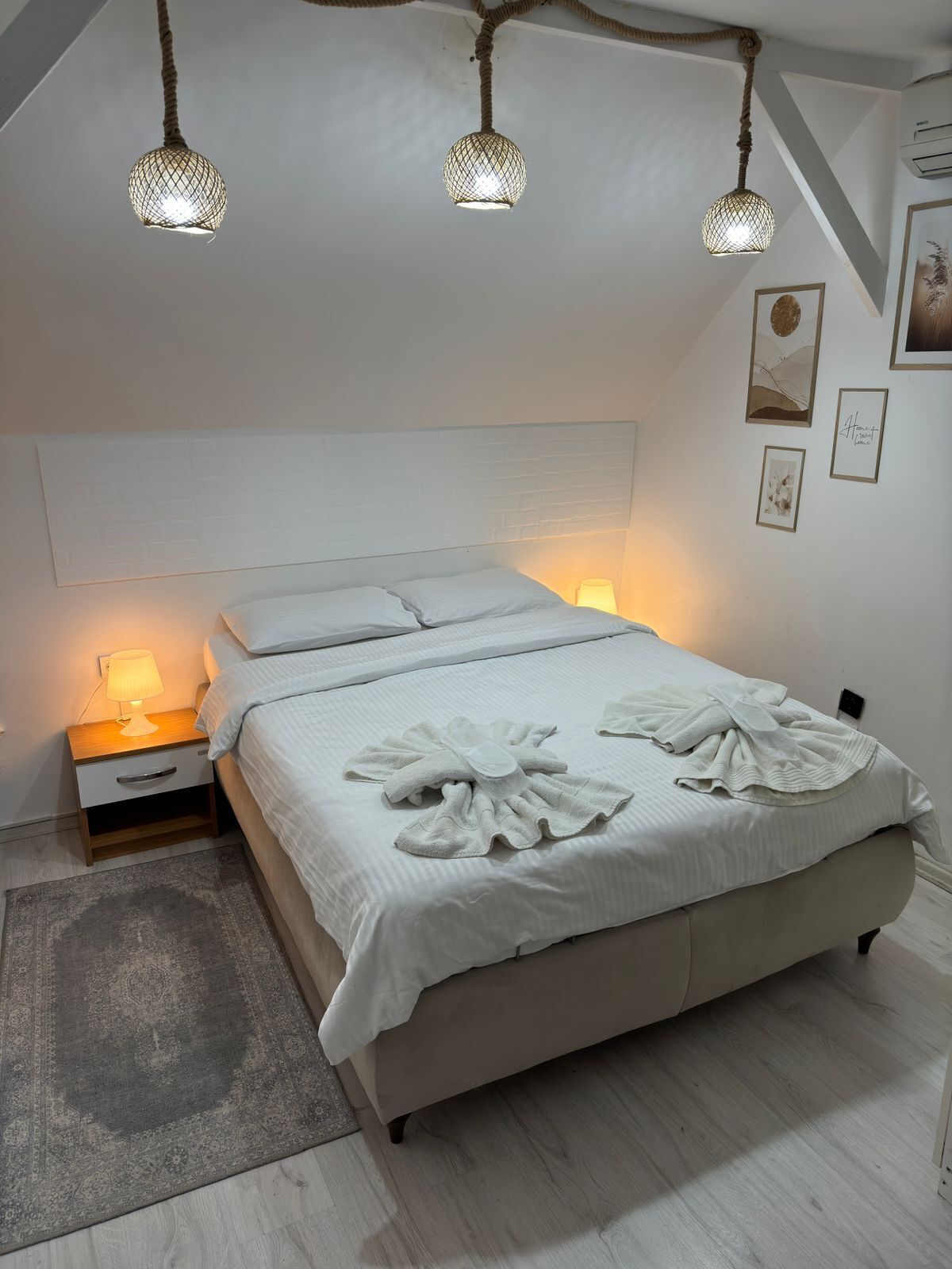 A bedroom with a bed, bedside lamps, and a hanging light fixture.