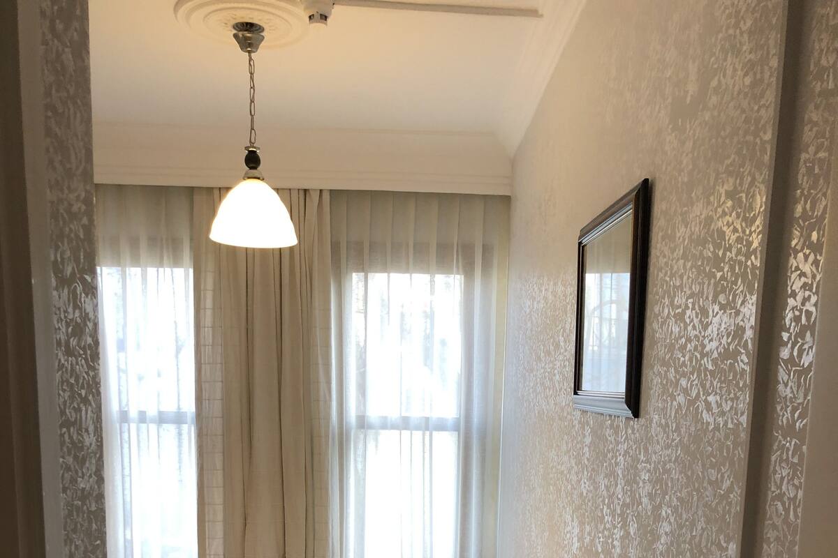A bedroom with a bed, curtains, a ceiling fan, and a framed picture on the wall.