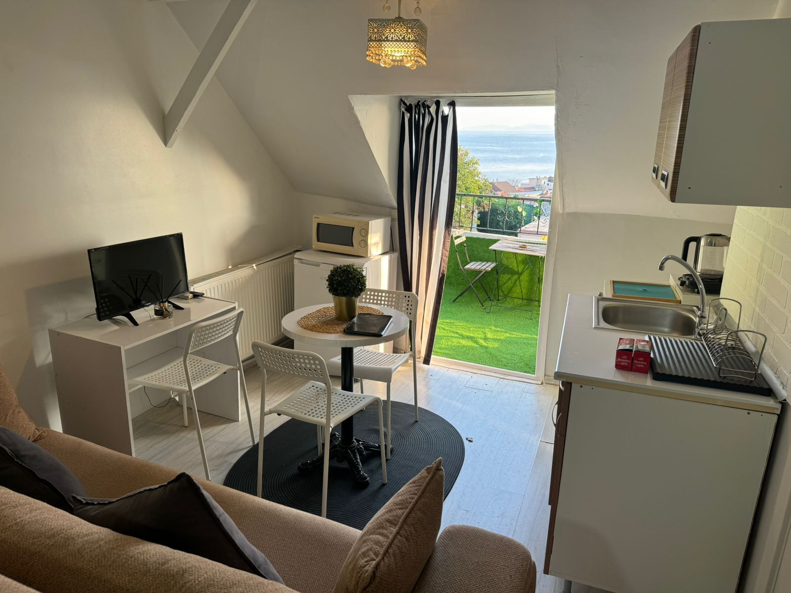 A compact living space with a kitchenette, a dining area, and a sofa.