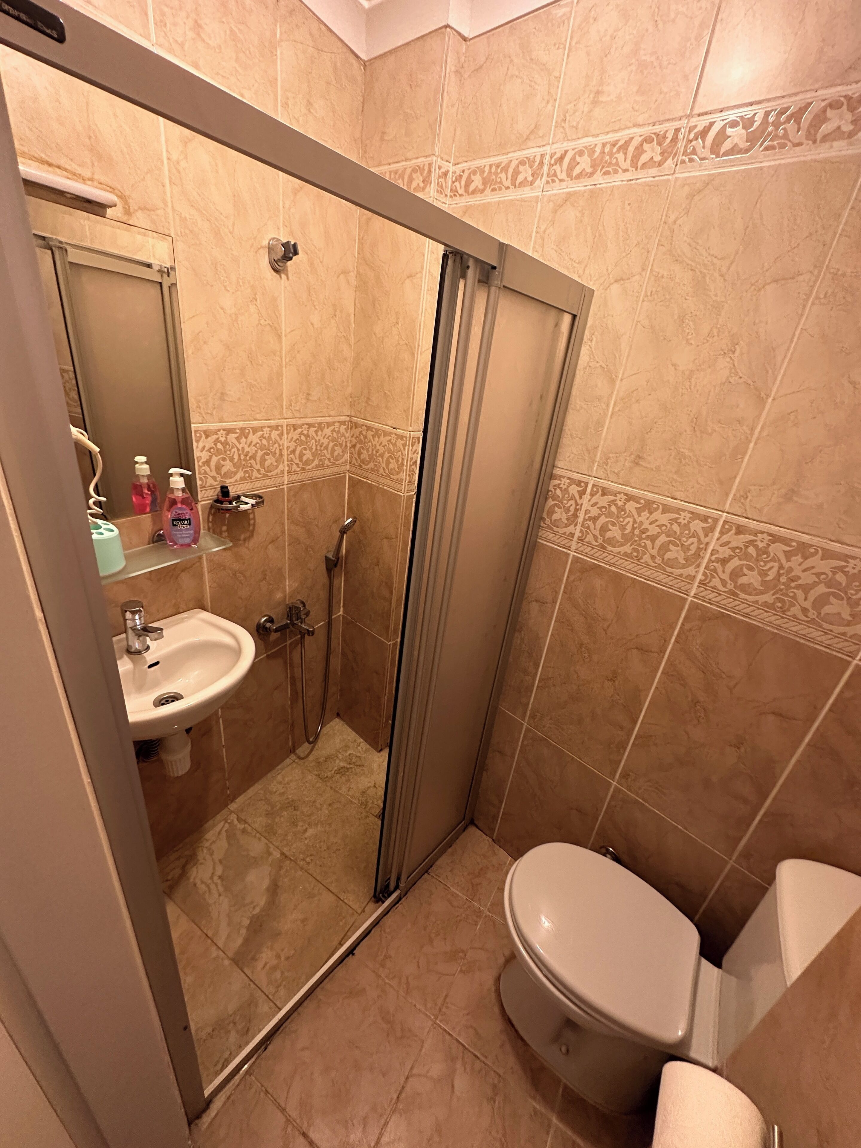 A bathroom with a shower, sink, and toilet.