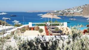 A coastal view with a pool area, lounge chairs, and umbrellas. - Seethrough Mykonos - Adults Only (Mykonos)
