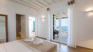 A hotel room with a bed, a bathroom, and a balcony with a view of the sea. - Seethrough Mykonos - Adults Only (Mykonos)