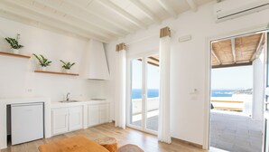 A modern kitchen with white cabinetry, a built-in refrigerator, and a wooden dining table. - Seethrough Mykonos - Adults Only (Mykonos)