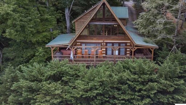 Une cabane avec une façade en bois, de grandes fenêtres et un balcon.