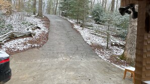 Une allée en béton menant à un garage, avec une voiture garée sur le côté gauche.