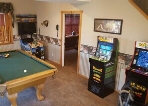 Ein Billardtisch mit einer Kugel, Spielautomaten und ein gerahmtes Bild an der Wand.