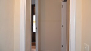 A narrow hallway with white walls and wooden flooring, leading to a door at the end. - Apartment Cos del Bou (Tarragona)