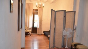 A hotel room with a wooden floor, a bed, a chair, a fan, and a partition wall. - Apartment Cos del Bou (Tarragona)
