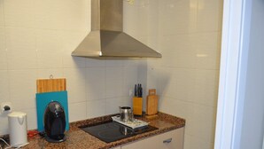 A kitchen with white cabinets, a granite countertop, a coffee maker, a kettle, and a toaster. - Apartment Cos del Bou (Tarragona)