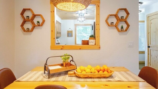 A dining area with a wooden table, chairs, a fruit bowl, and hexagonal wooden shelves with small plants. - Alpine in the Ozarks~ right off back 40 trails (Bella Vista)