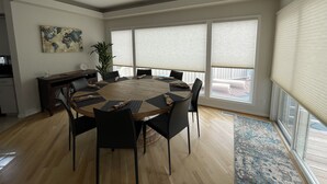 Un vaste espace dédié à la salle à manger, avec une table ronde, des chaises noires et une grande plante en pot.