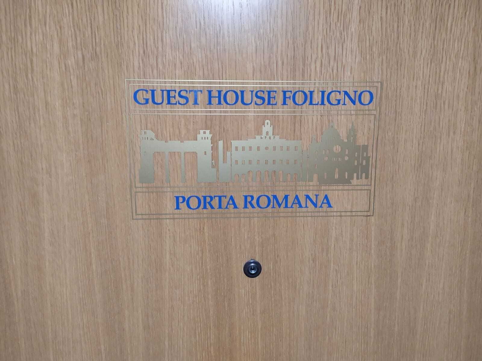 Una puerta de madera con un cartel que indica "GUEST HOUSE FOLIGNO PORTA ROMANA".