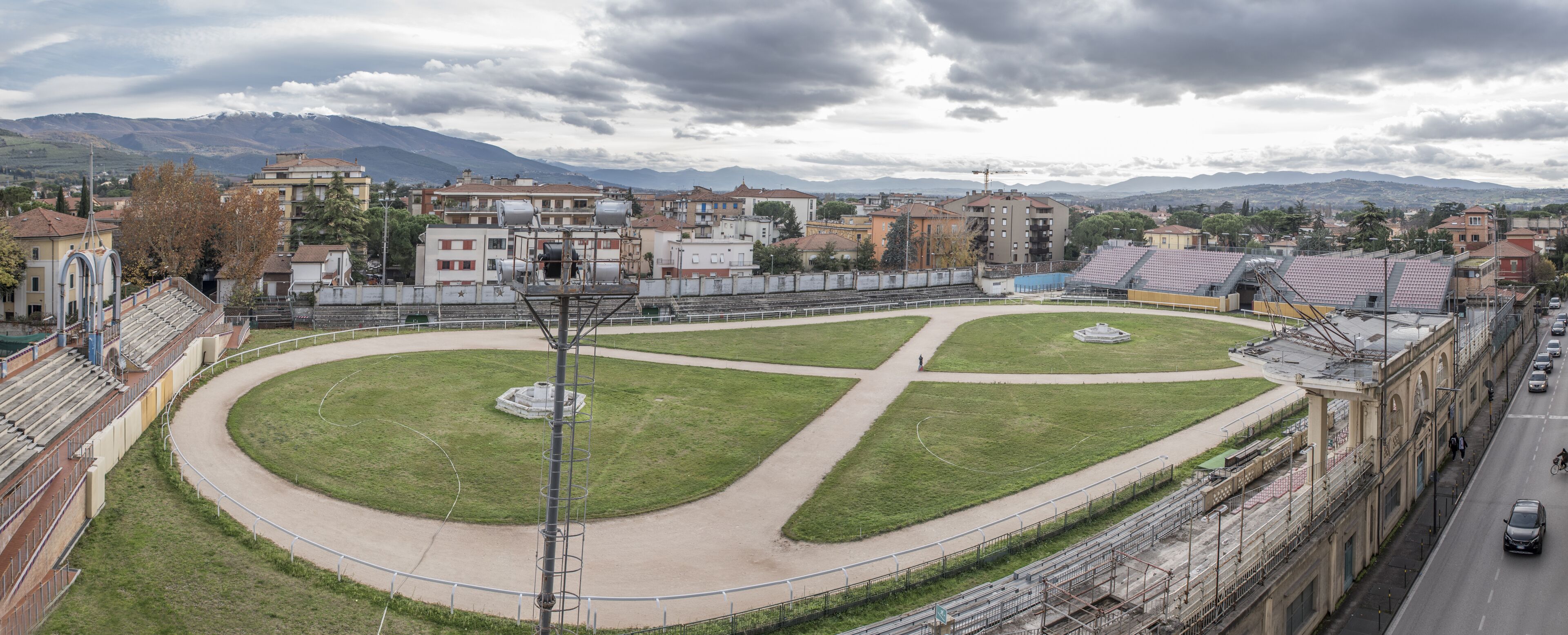 A stadium with a central grassy area and spectator stands.