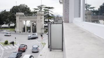 A busy urban street with a prominent archway labeled "STRENVORUM IMMORTALE NOMEN" and a bus stop shelter.