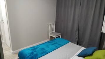 A bedroom with a bed, a chair, a TV, and curtains.