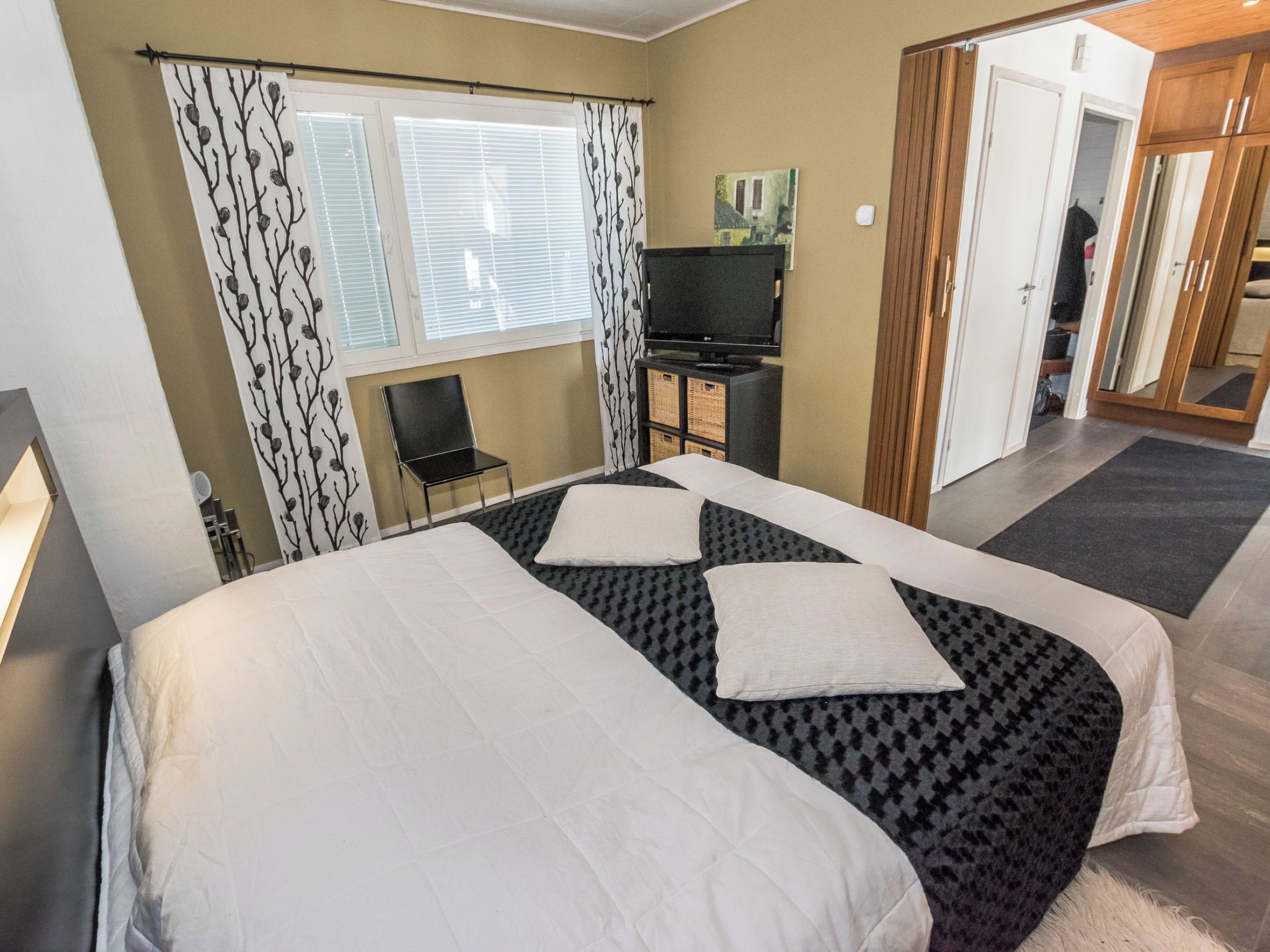 Una habitación de hotel con cama, televisión, silla y armario.
