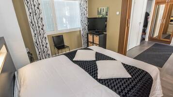 A hotel room with a bed, a TV, a chair, and a wardrobe.