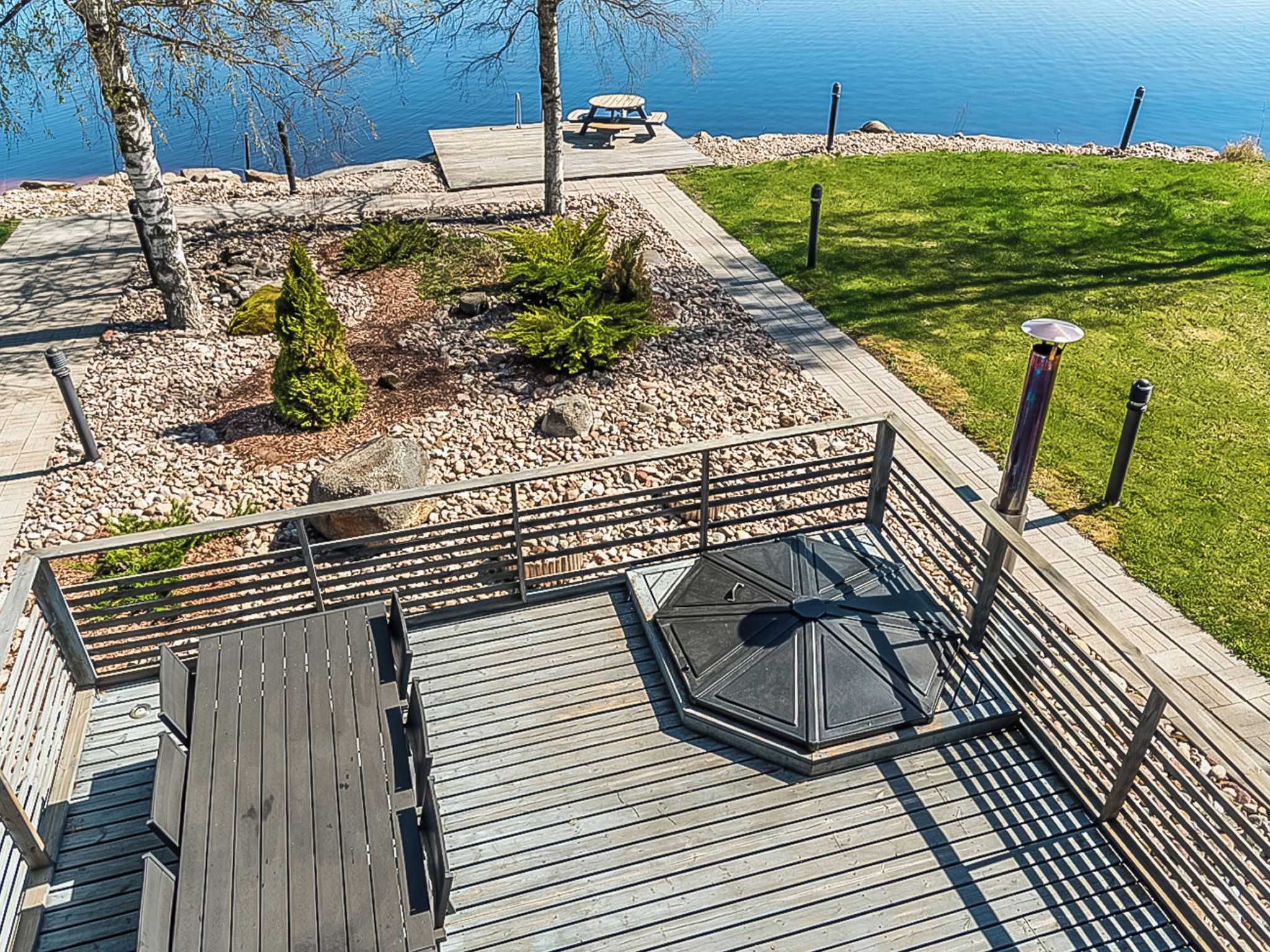 A wooden deck with a glass enclosure, a bench, and a picnic table.