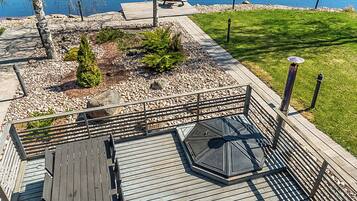 A wooden deck with a glass enclosure, a bench, and a picnic table.