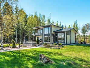 A modern two-story house with a large front porch, surrounded by a well-maintained lawn and trees. - Villa kaivopuisto by Interhome (Lavia)