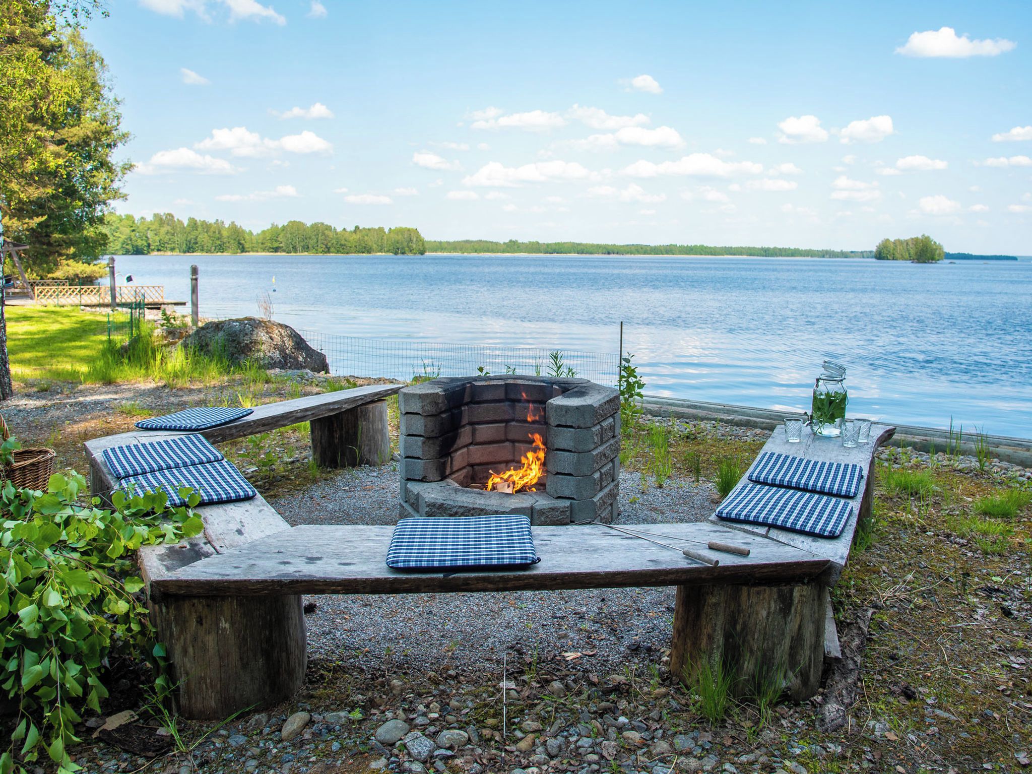 A lakeside outdoor seating area with a fire pit, benches, and a view of the lake.