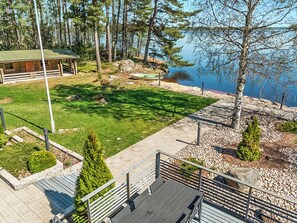 A wooden deck with a view of a lake and a cabin. - Villa kaivopuisto by Interhome (Lavia)
