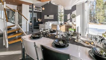 Un comedor moderno con una mesa blanca, sillas negras y una lámpara colgante grande.