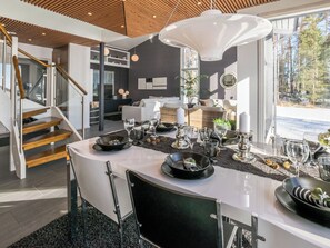 Ein moderner Essbereich mit einem weißen Tisch, schwarzen Stühlen und einer großen Pendelleuchte.