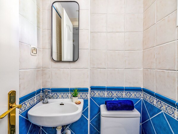 Un baño con lavamanos blanco, inodoro y espejo.