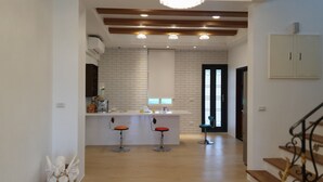 A spacious kitchen with a central island, wooden beams on the ceiling, and a chandelier. - Honeysuckle Family Castle (Wujie)