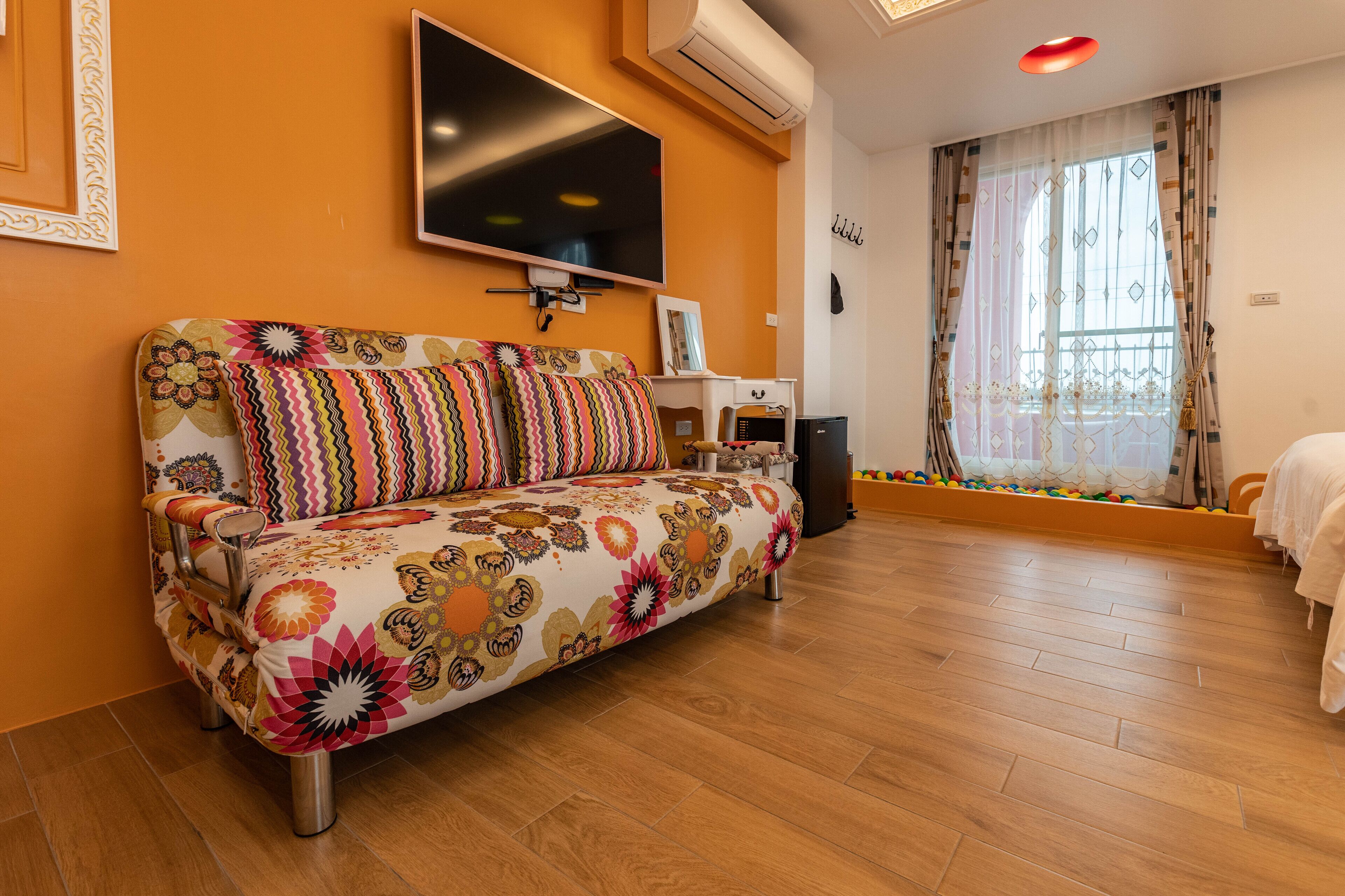 A modern living room with a sofa, TV, and a large window with curtains.