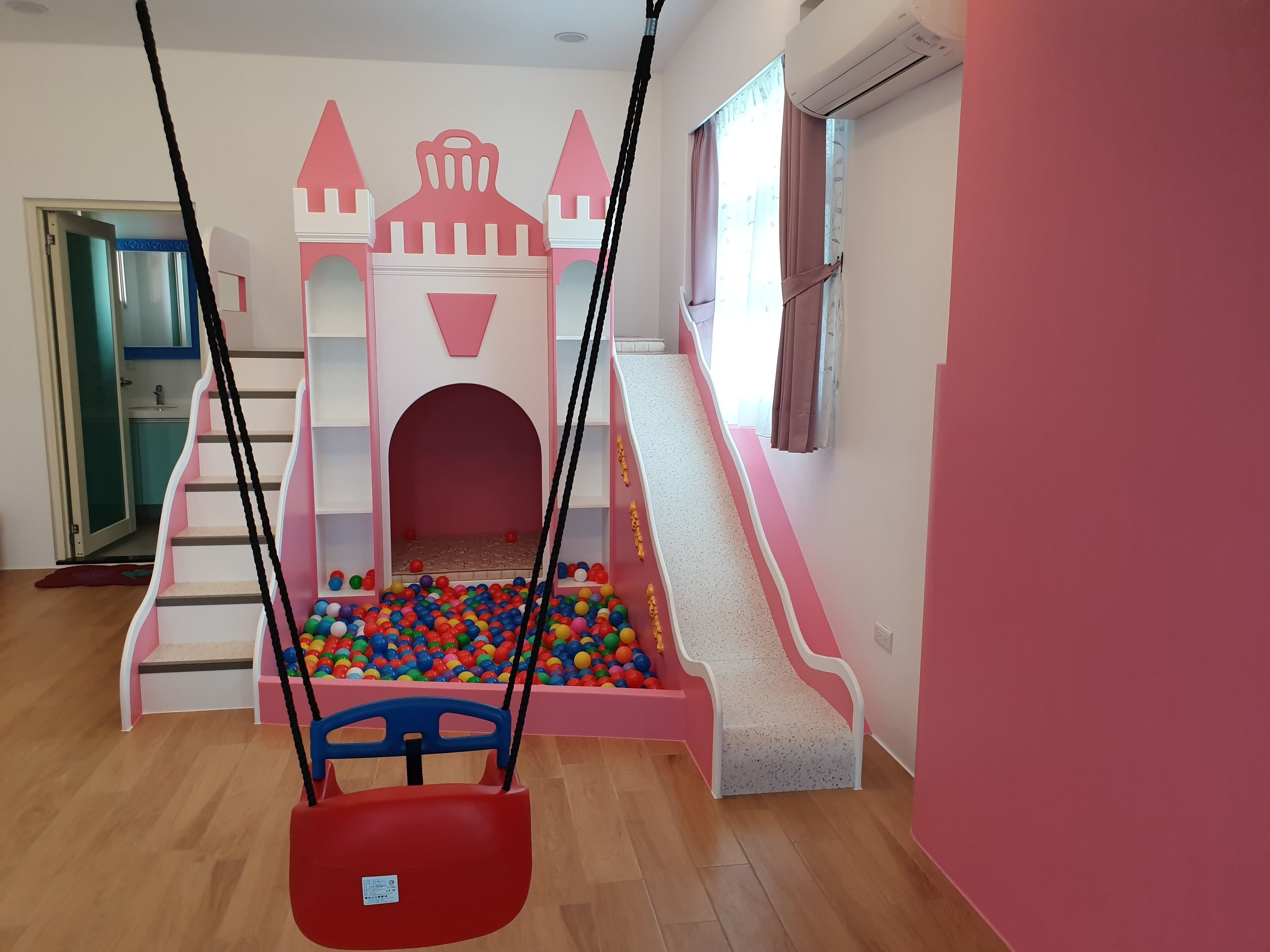 A children's play area with a slide, ball pit, and swing set.