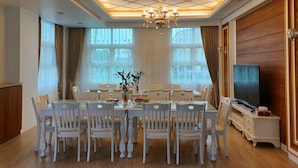A dining room with a high ceiling, chandelier, and large windows. - Honeysuckle Family Castle (Wujie)