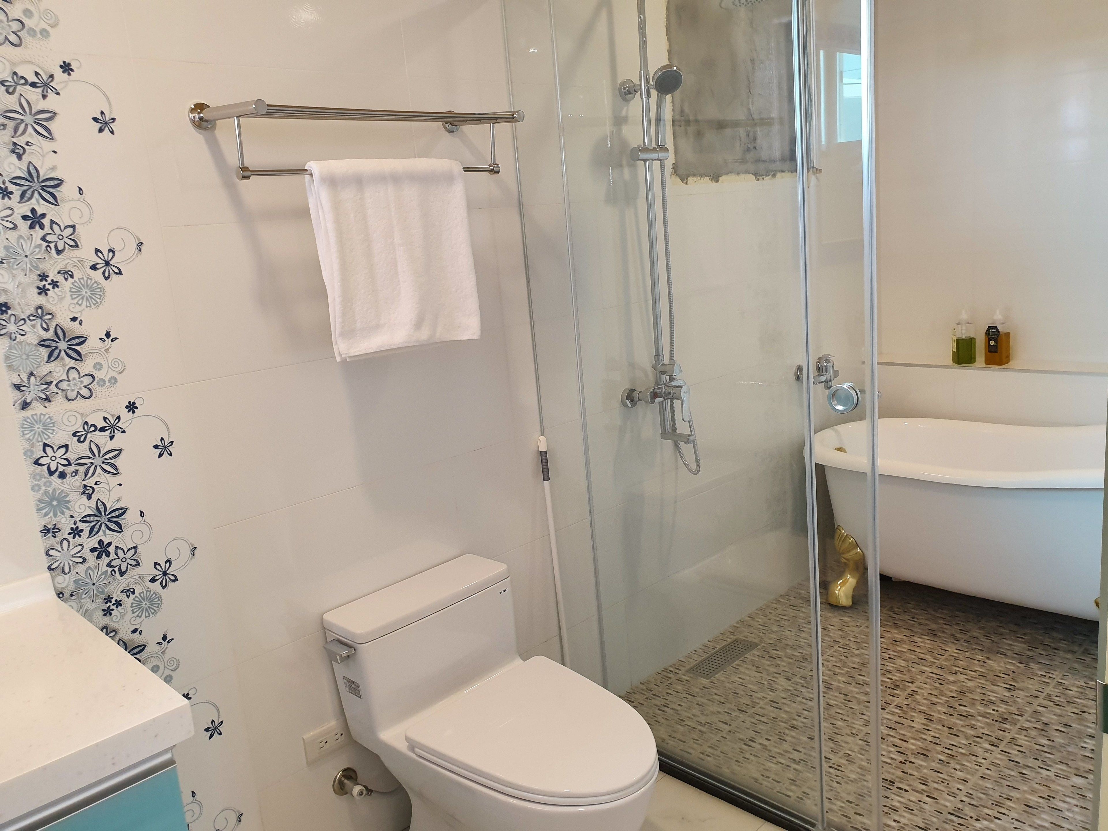 A bathroom with a toilet, a glass shower enclosure, a glass door, a sink, and a towel rack.