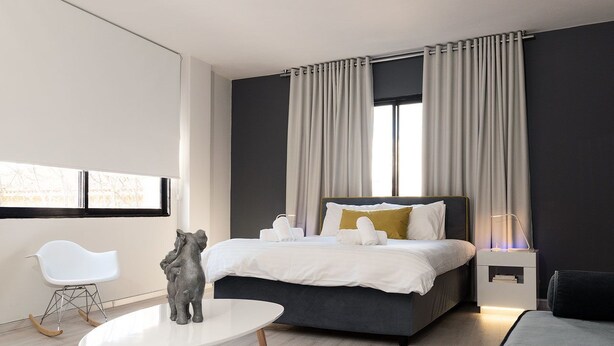 A modern bedroom with a bed, bedside table, and a small table with chairs. - Plaka Heart (Athens)