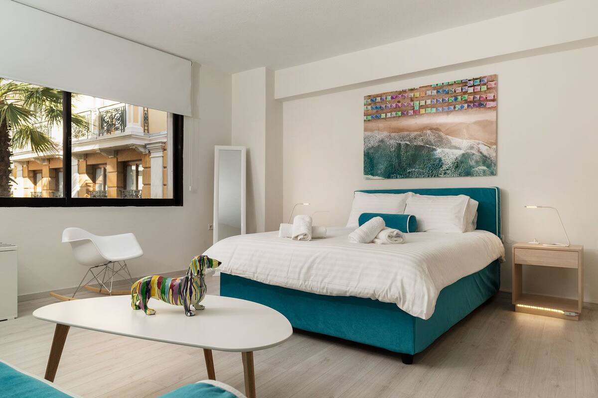 Una habitación de hotel moderna con cama, mesita de noche y vistas al balcón.