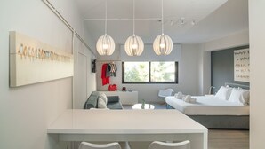A modern, well-lit room with a dining area, a sofa, and a bed. - Plaka Heart (Athens)