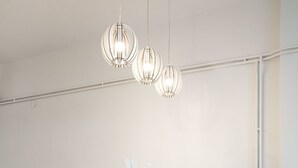 A modern kitchen with white cabinetry, a central island with stools, and pendant lighting. - Plaka Heart (Athens)