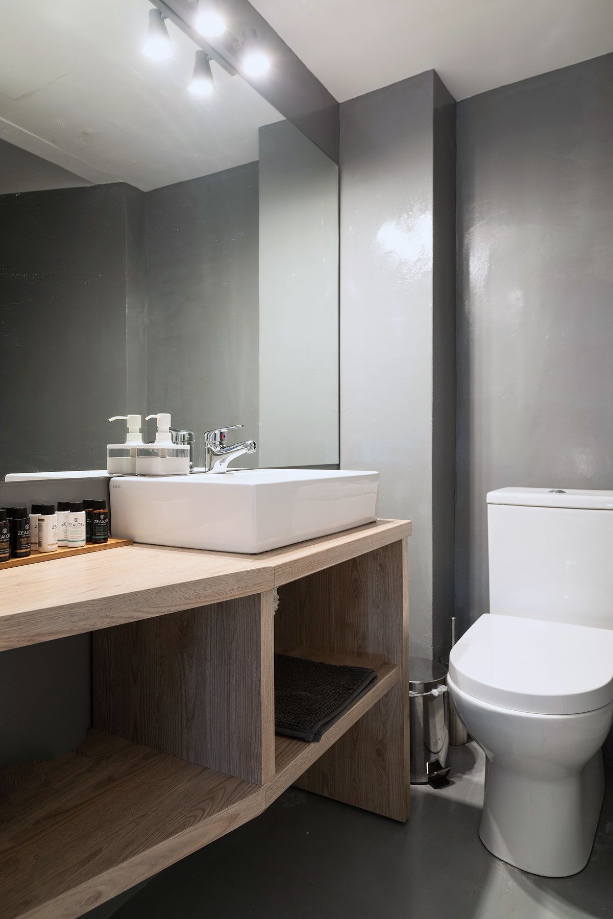 Un bagno moderno con lavandino, specchio e water bianchi.