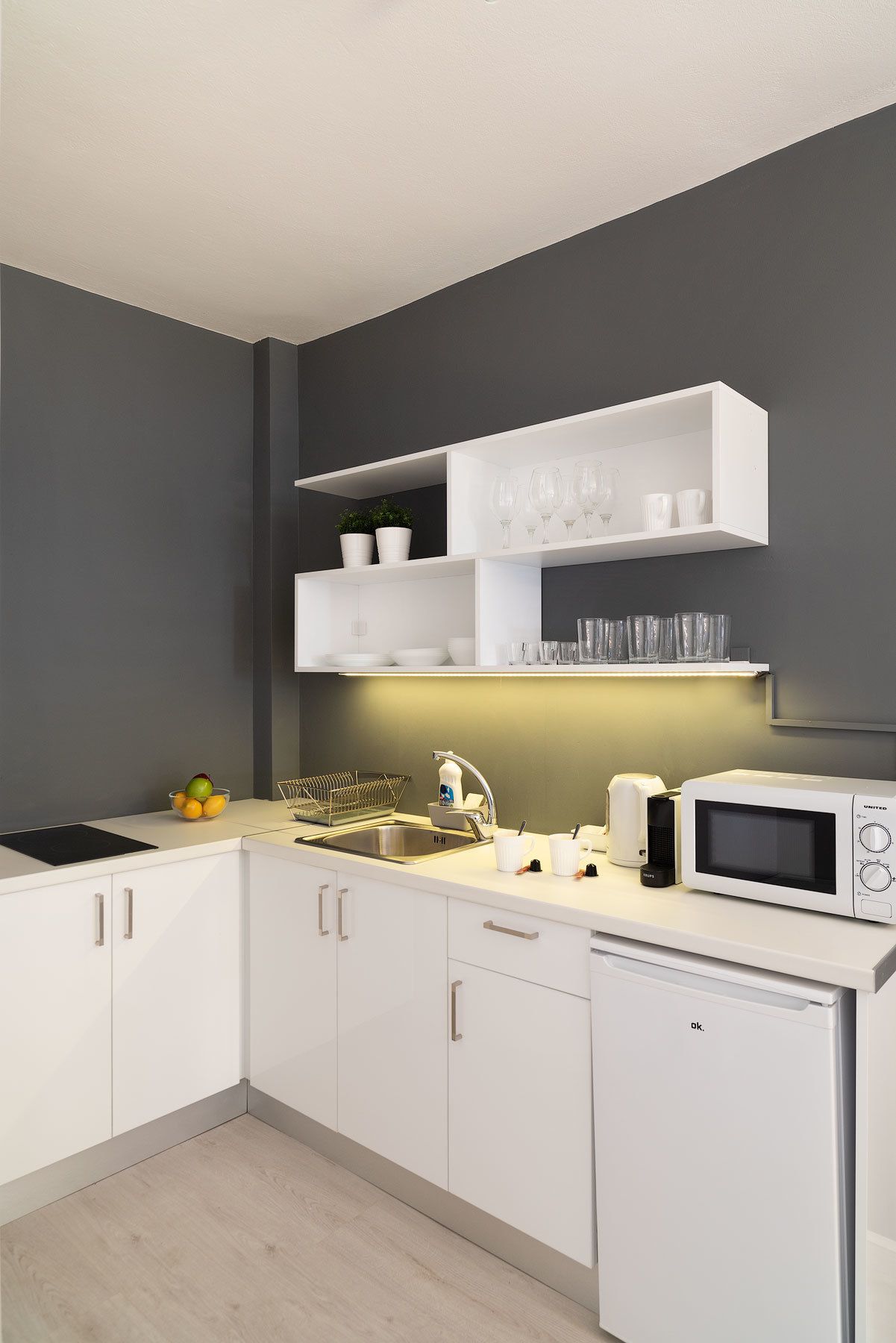A modern kitchen with white cabinets, a built-in microwave, and a dish drying rack.