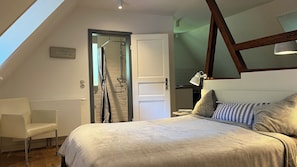 Une chambre à coucher avec un lit, une chaise, une porte et une lucarne.