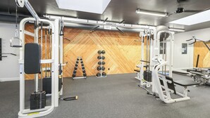 A gym with various exercise equipment, a wooden wall, and a ceiling with a skylight.